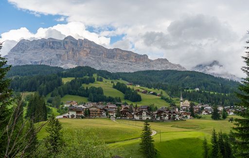A tranquil scene of a rural mountain town, with small houses in the distance, Dolomites, Italy