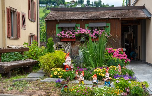 The colorful flowers bushes shrubs and a small house in the background