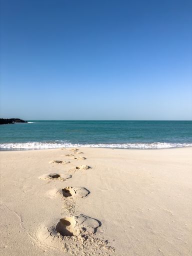 Foot steps in beach sand walking back from sea
