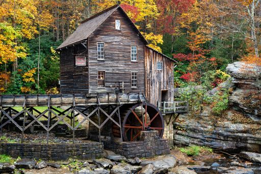A rustic wooden grist mill with water wheel in the foreground of Babcock State Park