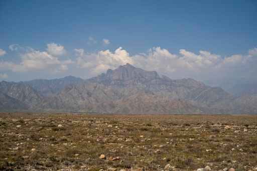 A landscape of a valley surrounded by rocky hills on a sunny day