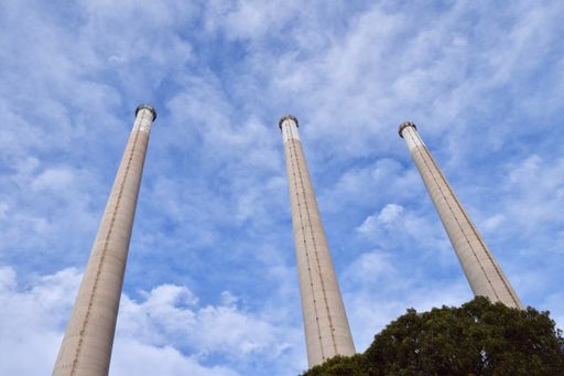 A low angle shot of the three Smoke Stacks in Morro Bay with blue sky and clouds above