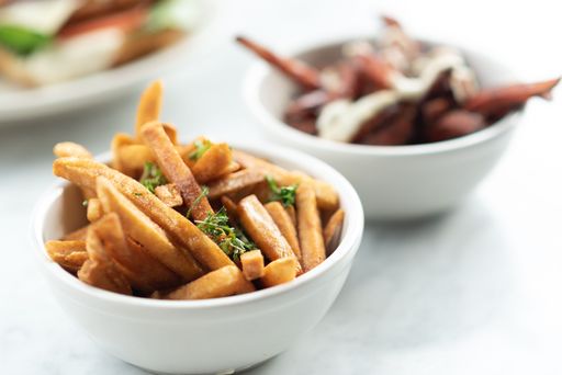 A closeup shot of fries with seasonings in a white bowl on a table