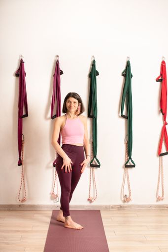 A young fit Armenian female posing on background of yoga hammocks in a studio