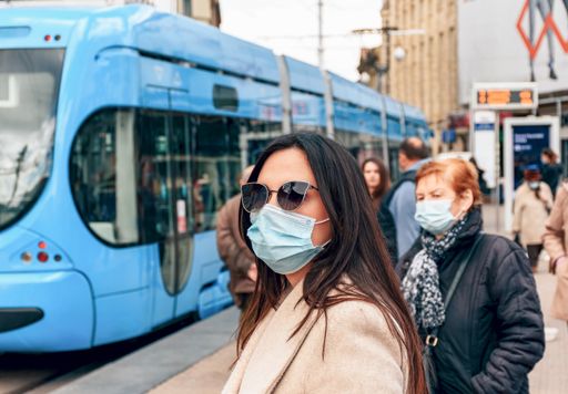 Young woman wearing protective face mask in city. Waiting on tram station, public transport, real people, covid, corona virus. Zagreb, Croatia.