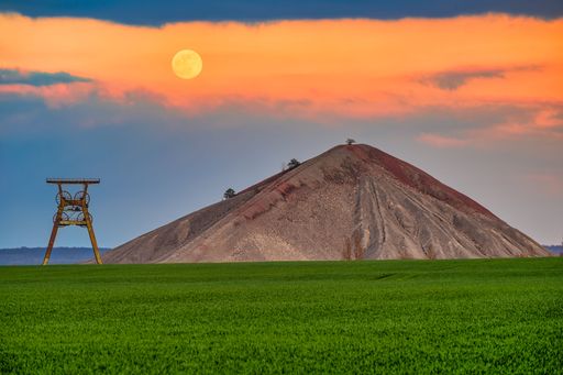 a view of an overburden heap in saxony-anhalt with a winding tower at moonrise