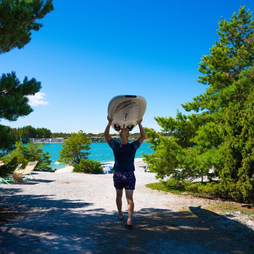 A young woman is walking towards the beach, carrying a surfboard in a horizontal position atop her head