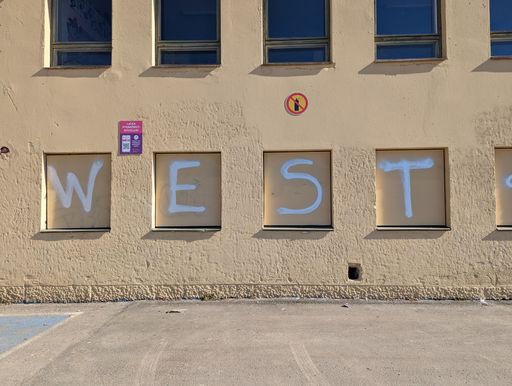 A close-up of a painted mural on the side of a building, the inscription reads "West"