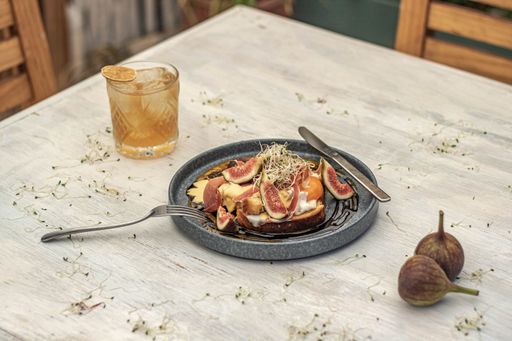 A closeup of fig and jam toast on a rustic table with golden drink