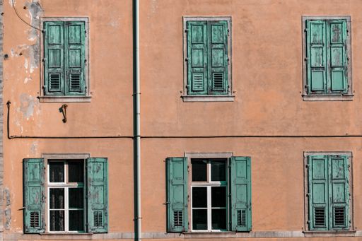 A shot of an orange building facade with green wooden window shutters
