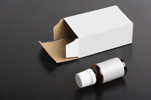 A closeup of a child dietary supplement glass bottle with a pack on a black table