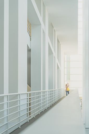 A woman taking pictures inside of a beautiful architecture space. The white walls of the building transmit us serenity and calm.