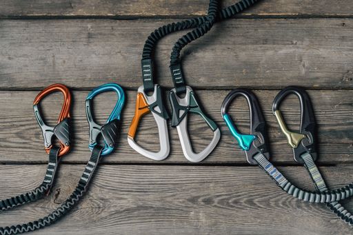 Top view of via ferrata equipment on a wooden table. Climbing gear like carabiner, sling and other for klettersteig climbing.