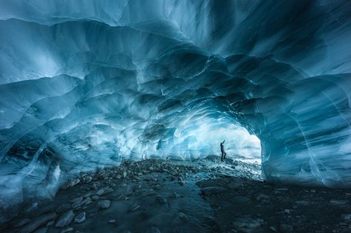 A hiker silhouette exploring an ice cave in the Furgg glacier in Zermatt, Wallis, Switzerland