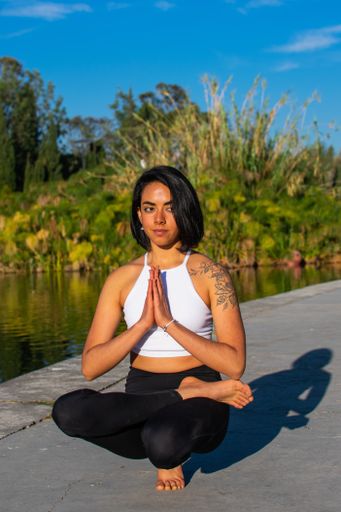 An attractive slim Latina from Mexico doing yoga in the morning in the park with a lake in the background - surrounded by nature