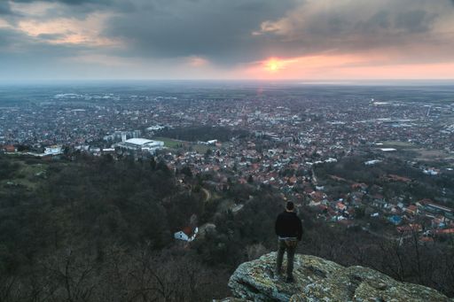 A hiker standing on the cliff above the Vrsac city in Serbia at sunset
