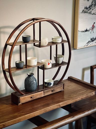 A wooden table with a set of shelves, each containing six small ceramic bowls