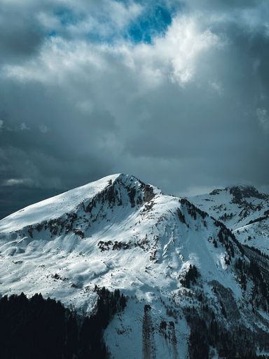 A scenic view of majestic snow-capped mountains against a cloudy sky.