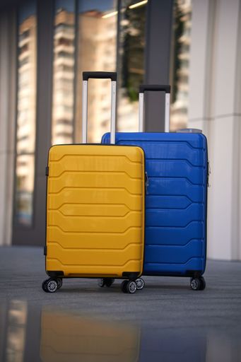 The yellow and blue suitcases on the street in front of a building.