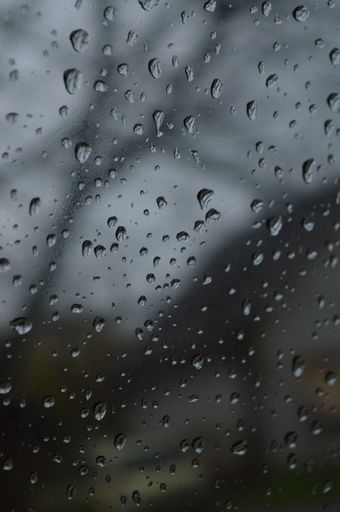 A vertical shot of rain droplets on a window