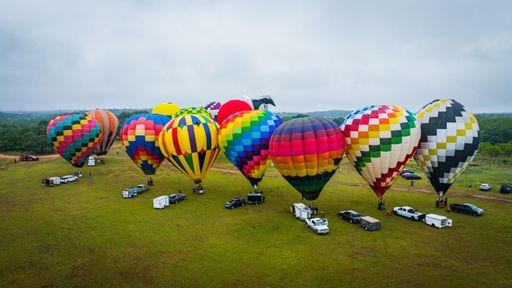 An aerial view of a colorful hot air balloons on a grassy field