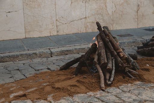 A small bonfire on the ground with a building on the background