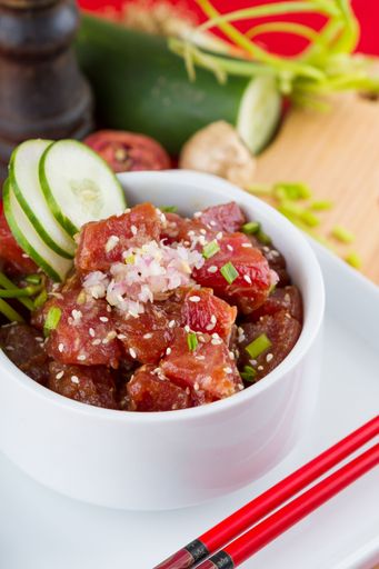 A plate of freshly prepared Poke Bowls on a wooden board, presented with chopsticks on the side