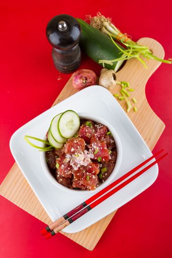 A plate of freshly prepared Poke Bowls on a wooden board, presented with chopsticks on the side