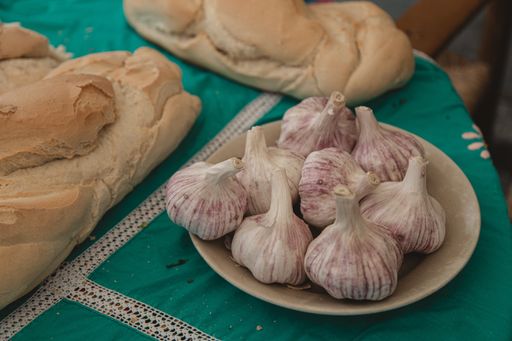 A closeup of garlic heads in a plate on the table with bread loaves under the lights
