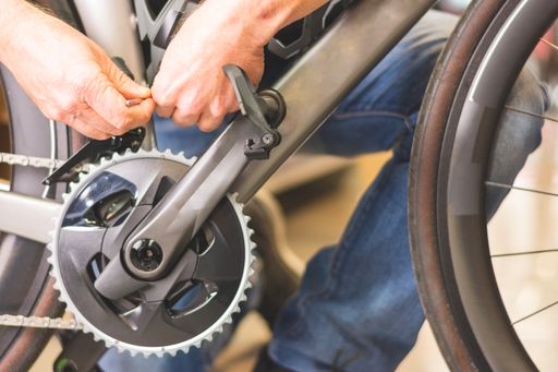 A closeup shot of a mechanic adjusting a piece of the centre of the bike with a tool