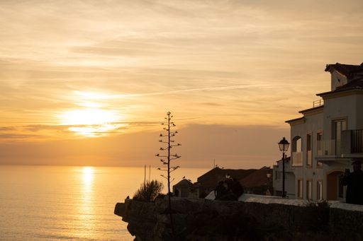 A beautiful sunset sky over a seashore with houses in Nazare, Portugal