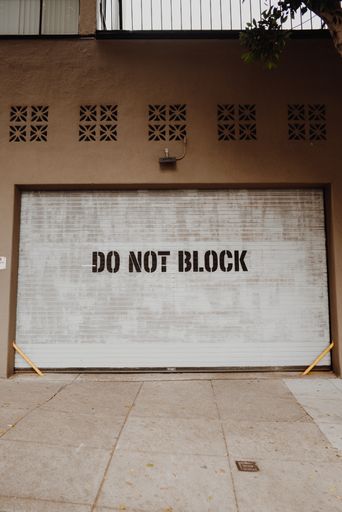 A closeup vertical shot of a garage door with writing "DO NOT BLOCK" on it
