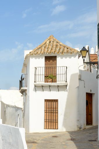 A vertical shot of a white house in Vejer de la Frontera under the sunlight and a blue sky in Spain