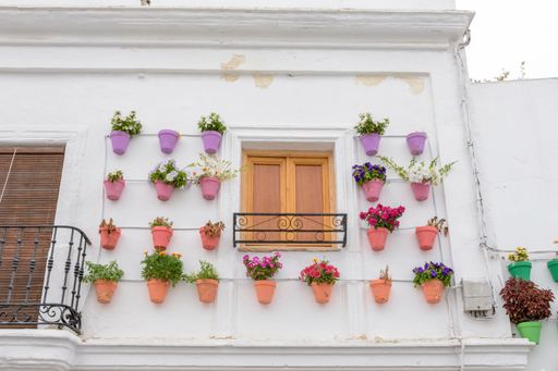 A white building wall decorated with many potted flowers in Vejer de la Frontera, Spain