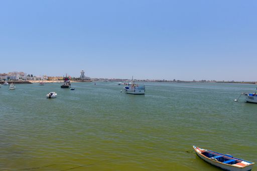 A view of Isla Cristina from the port with fishing boats and the lighthouse in the background