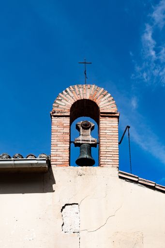 A bell in the arch of a hermitage against the blue sky