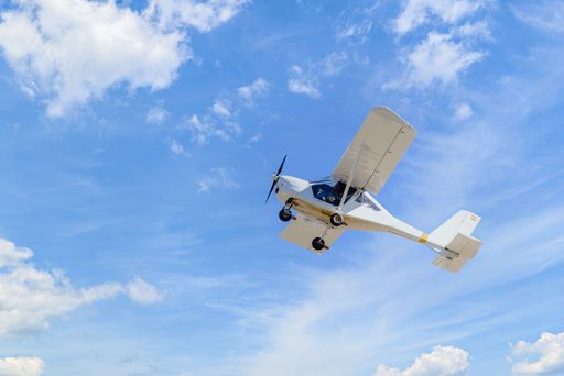 An airplane flying against a cloudy blue sky