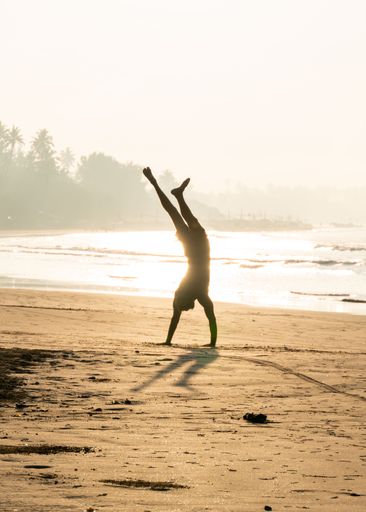 A silhouette of a man performing a handstand in the tropical paradise of Sri Lanka.