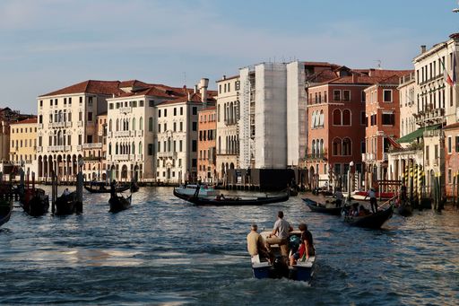 A group of people in small vessels navigating through a canal in Venice