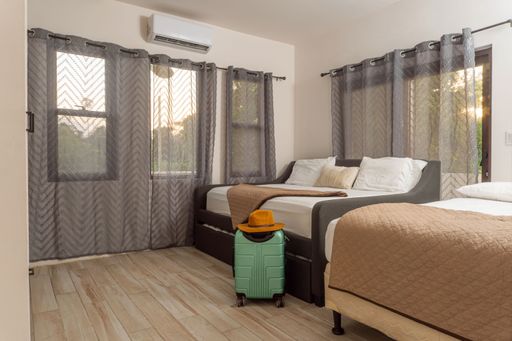 A lodging room and a travel suitcase with a hat on top, traveler concept.