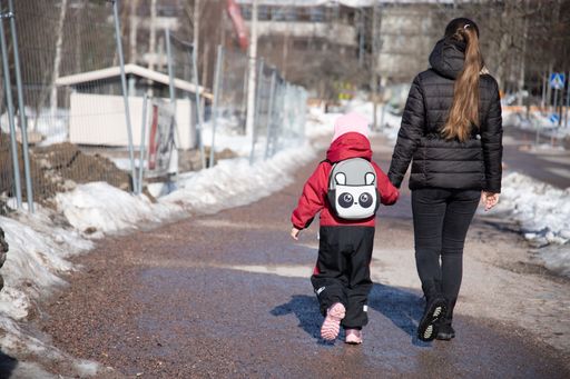 The mother with her kid walking down the snow-covered street