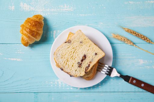 An overhead shot of whole wheat loaf and croissant on a blue wooden table
