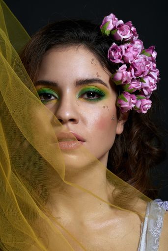 A portrait of an Italian woman with vibrant eye makeup and a yellow veil against a dark background