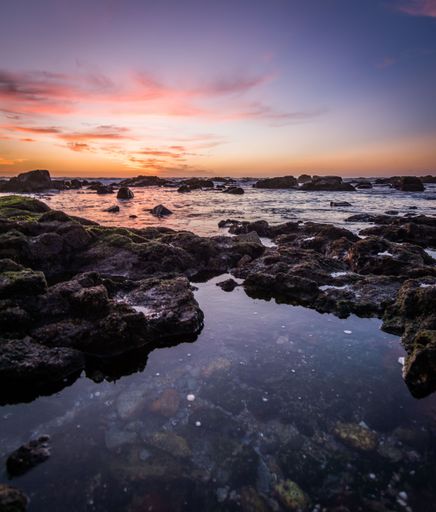 A beautiful view of colorful skies during the sunset over the stones near the coastline