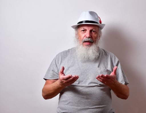 A retired American male with a long white beard holding both hands out