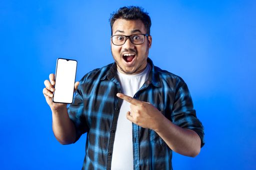 excited indian man wearing eye glasses showing blank mobile screen and pointing finger