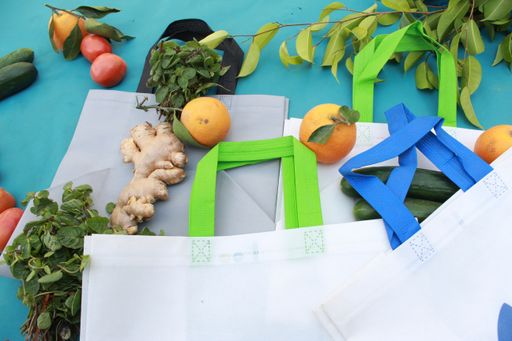 White shopping bags and fresh vegetables on blue background