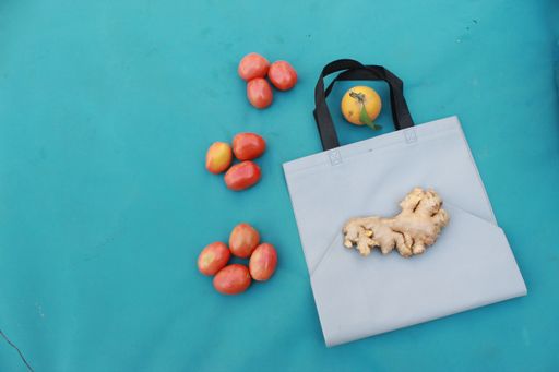A white shopping bag and fresh fruits and vegetables on blue background