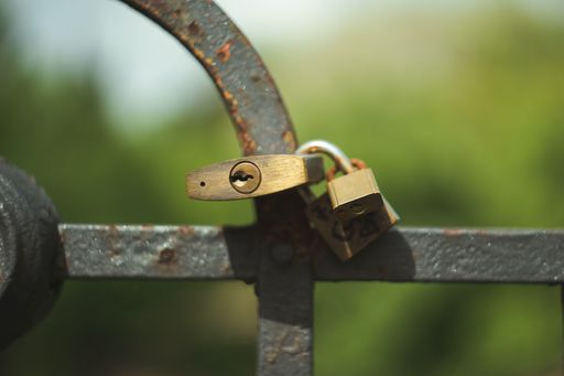 A close-up image of a  metal fence with an old-fashioned lock firmly secured in place