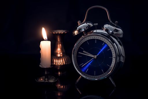 A closeup shot of an alarm clock with a candle \